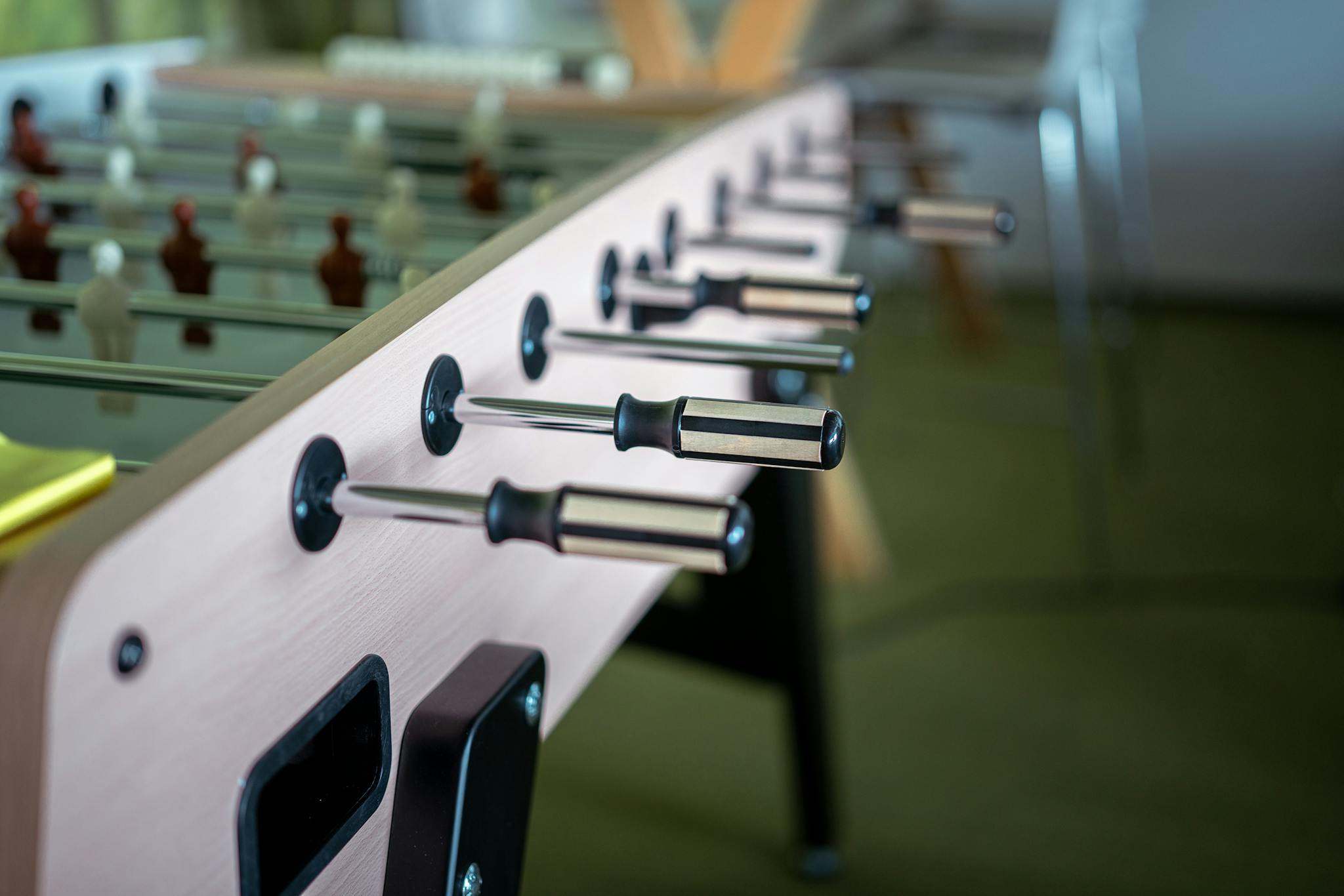 Detailed view of foosball table handles in an indoor setting, perfect for game enthusiasts.